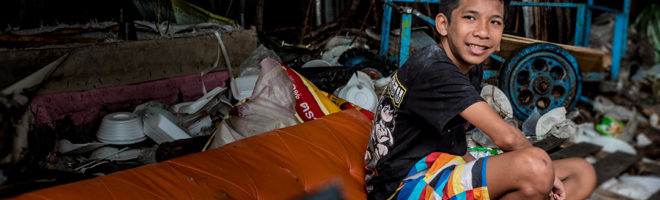 Boy sitting in a torn couch in a slum area